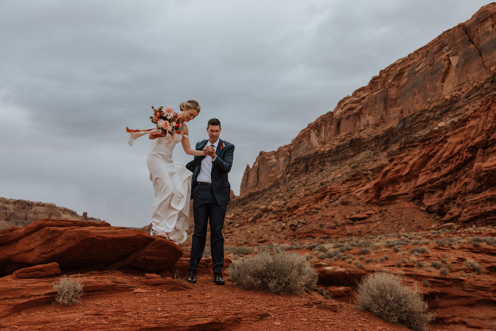couple walks along red rocks at Dead Horse Point State Park