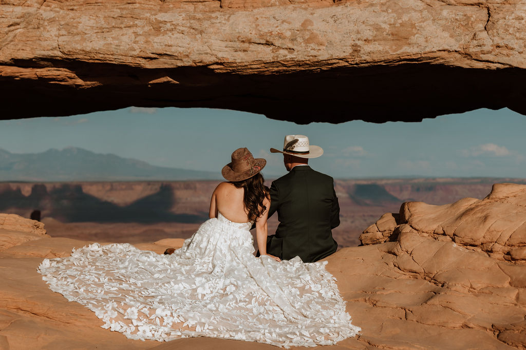 couple sits under arch at Canyonlands National Park elopement