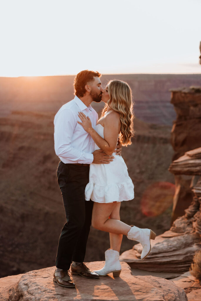 couple kisses on ledge at Dead Horse Point Moab