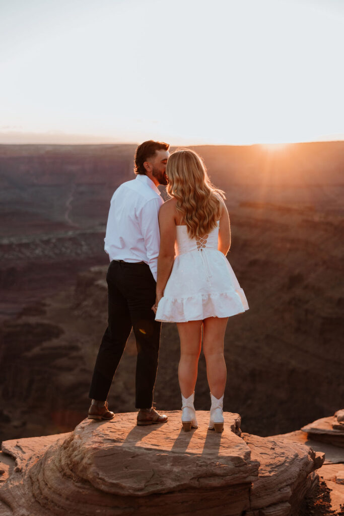 couple kisses on ledge at Dead Horse Point Moab