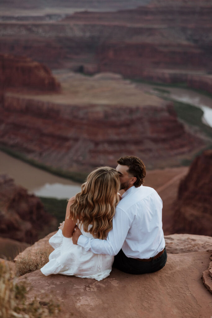 couple kissing on rocky ledge overlooking Dead Horse Point