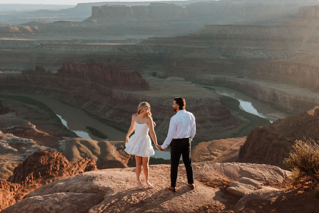couple stands on cliff edge at Dead Horse Point engagement