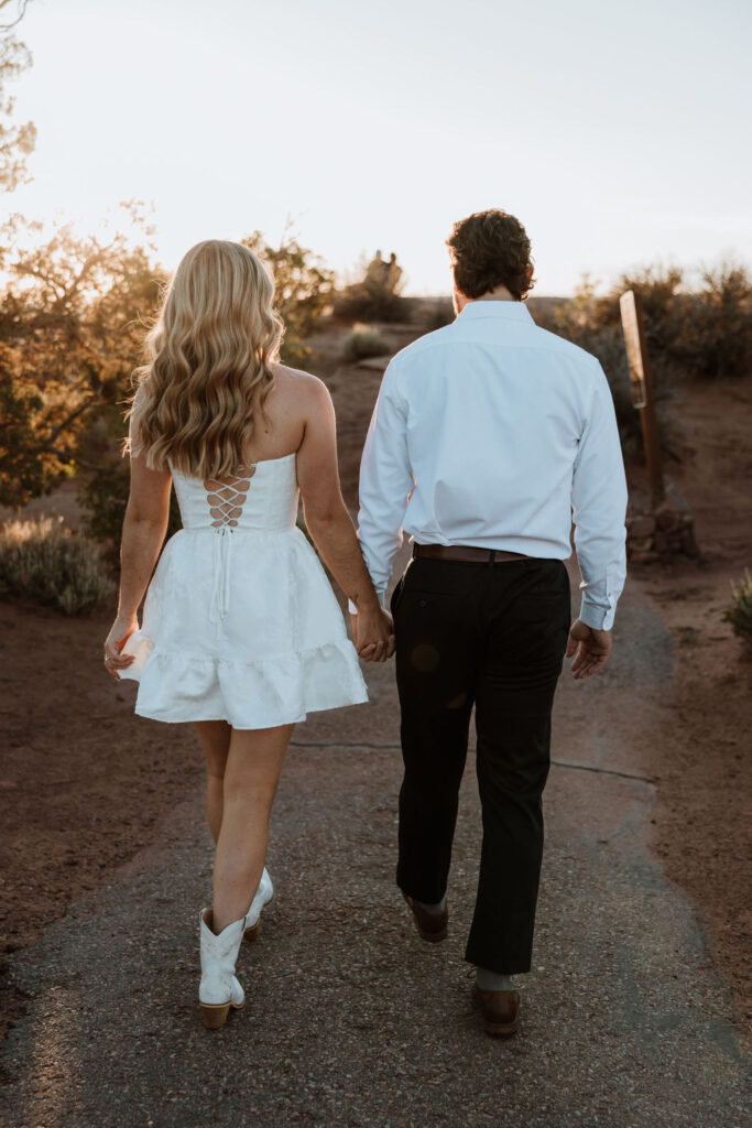 couple walking and holding hands along rocky path