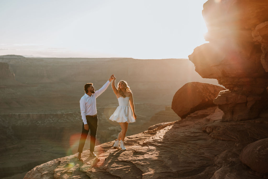 man spins woman on rocky ledge at Dead Horse Point