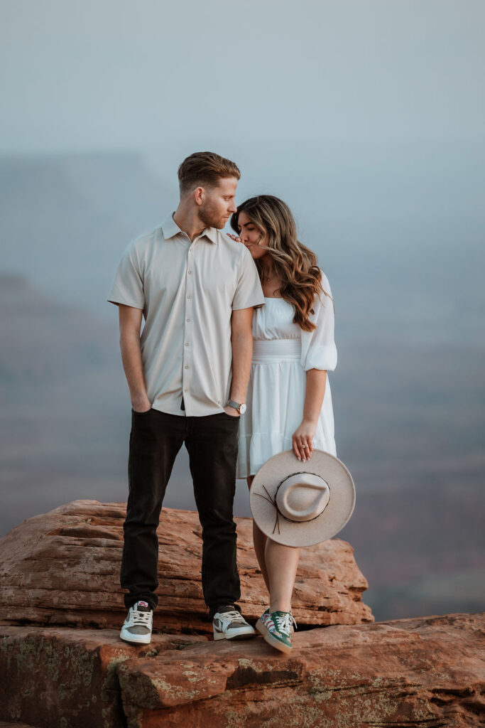 woman kisses man's shoulder on rocky ledge at Dead Horse Point
