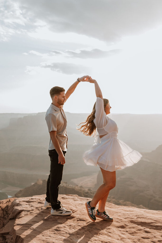 man spins woman on rocky ledge at Dead Horse Point