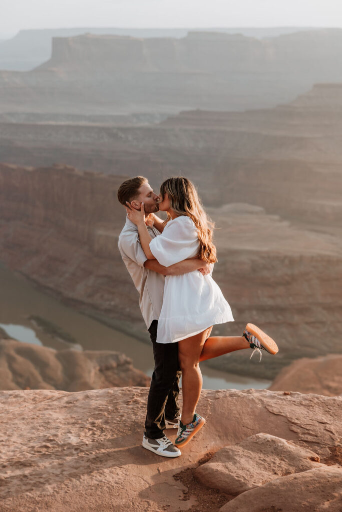 couple kissing on rocky ledge at Dead Horse Point