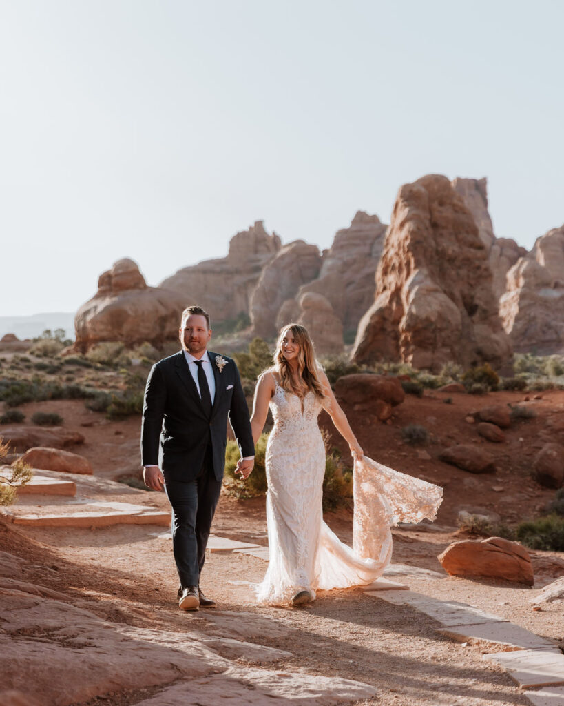 couple walks holding hands at Arches National Park