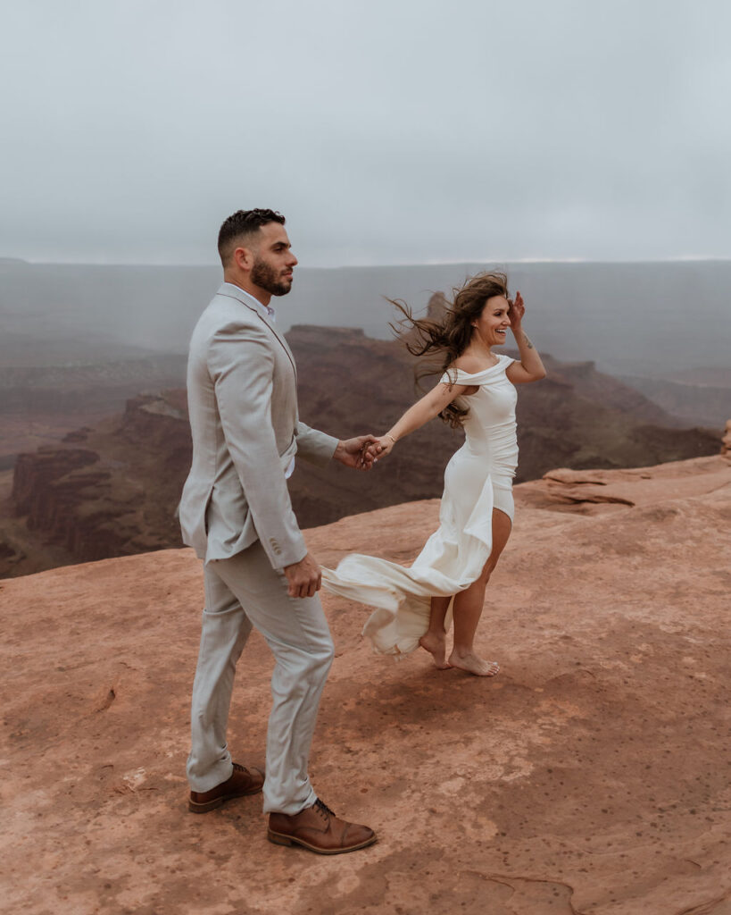 couple posing on canyon overlook after wedding in moab