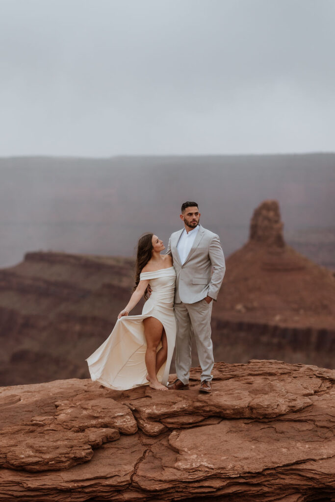 couple posing on canyon overlook after wedding in moab