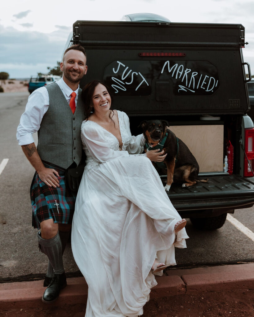 couple posing with dog and a car saying "just married"
