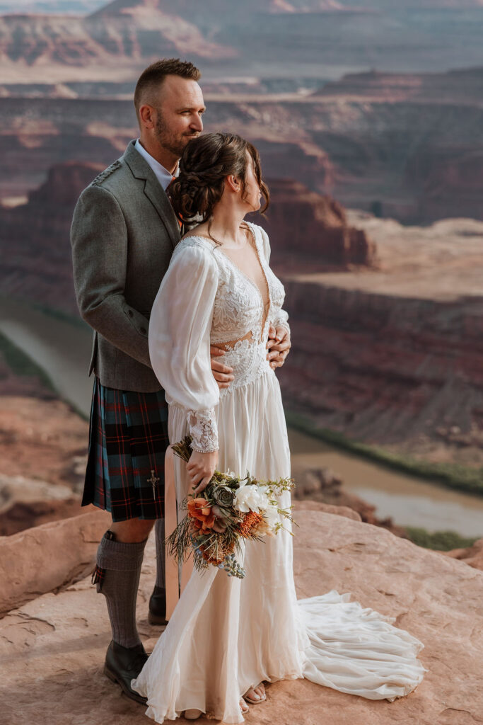 couple standing on ledge overlooking Moab's red rock landscape