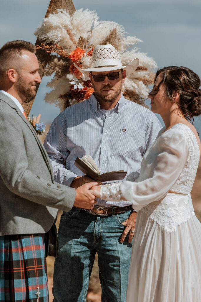bride and groom holding hands during ceremony at under canvas moab