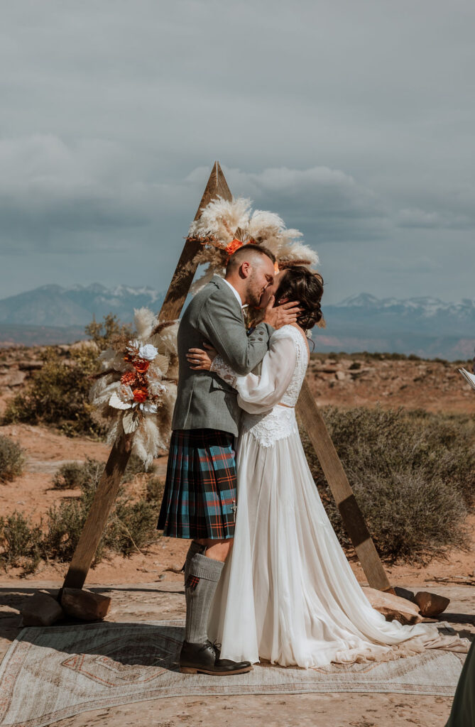 couple kiss during wedding ceremony under canvas moab
