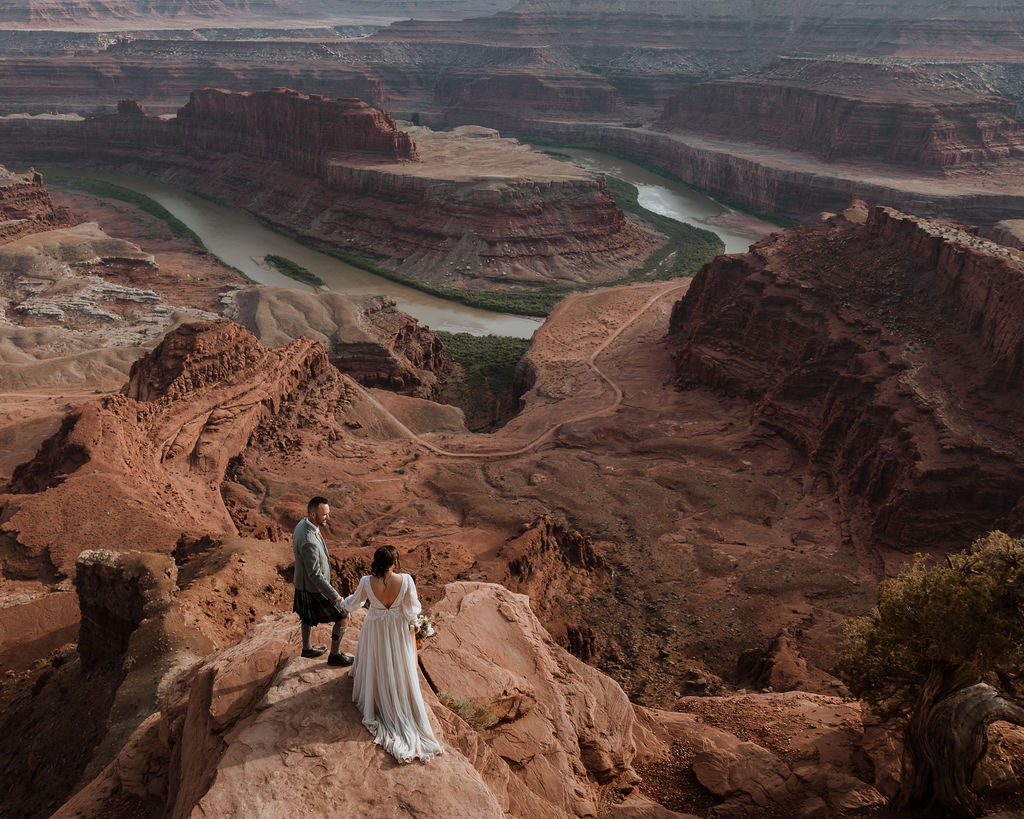 couple standing on ledge overlooking Moab's red rock landscape