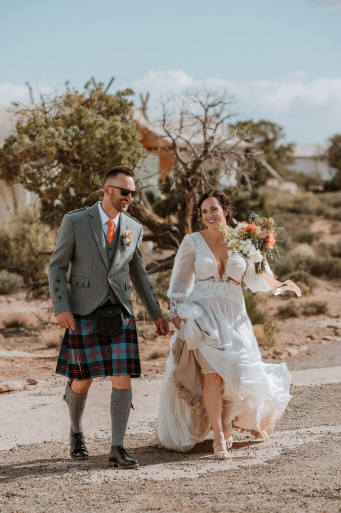 couple walking along rocky path to reception under canvas moab
