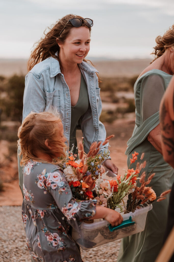 women packing up and carrying wedding flowers out of the wind