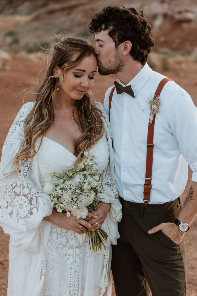 groom kisses bride's forehead during sunset photos
