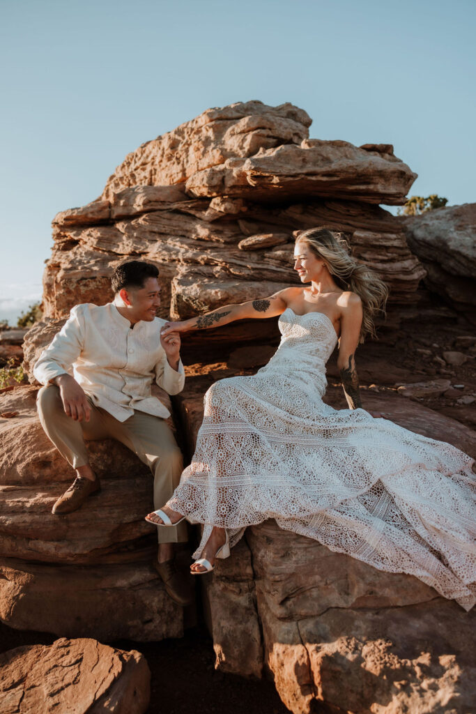 couple sitting on ledge of rocky Moab landscape