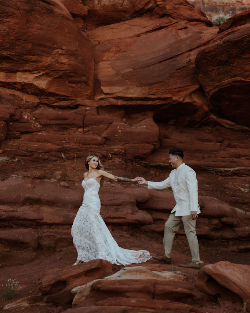 couple holding hands walking along the rocky landscape