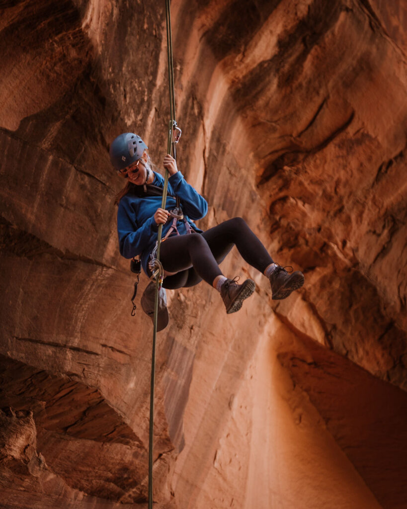 woman rappelling down side of Moab rock 