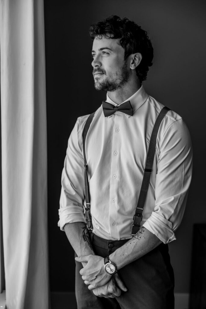 groom looking out the window after getting ready