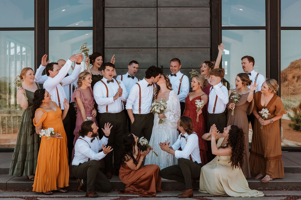 wedding party celebrating when bride and groom kiss