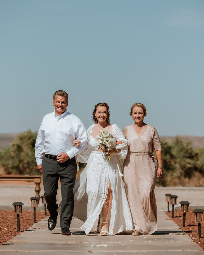 bride walks down the aisle with mother and father