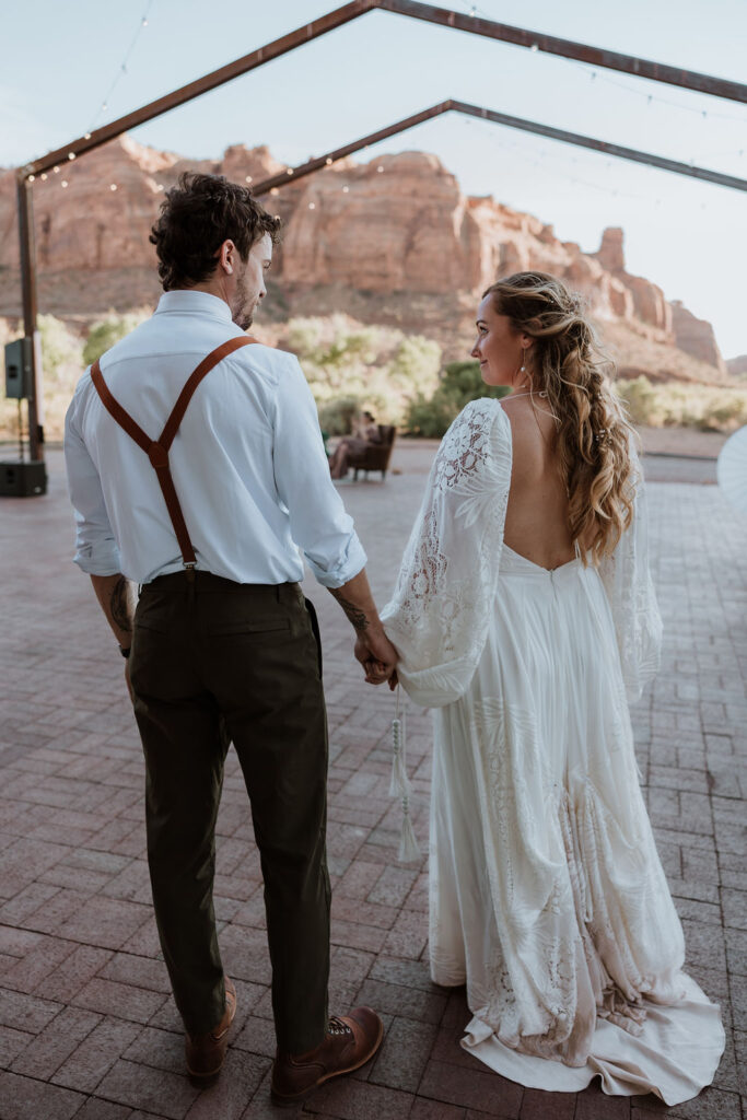 couple holding hands walking into reception