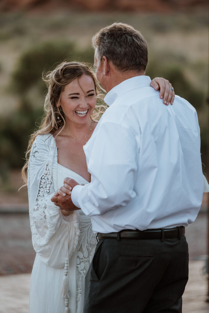 bride laughs while dancing with father