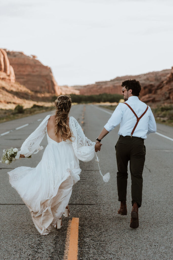 couple runs along road in the middle of Moab desert 