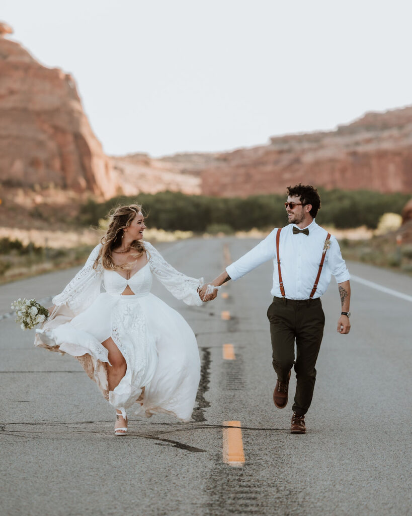 couple runs along road in the middle of Moab desert 
