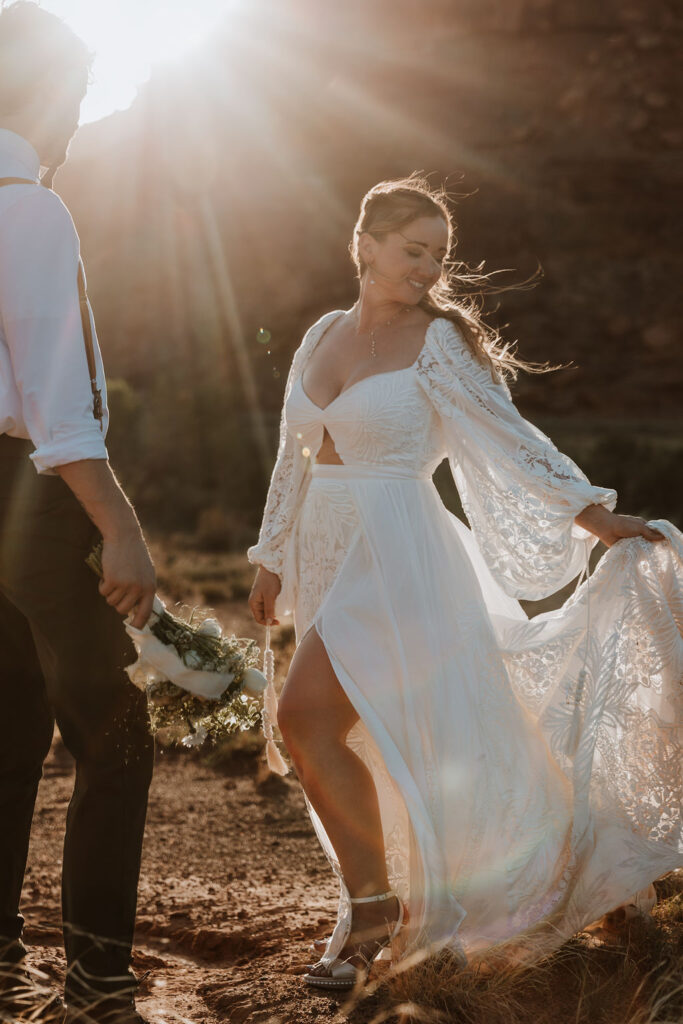 bride holding train of dress during setset pictures
