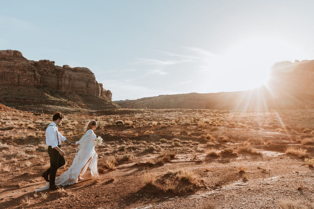 couple walks along rocky Moab desert during sunset