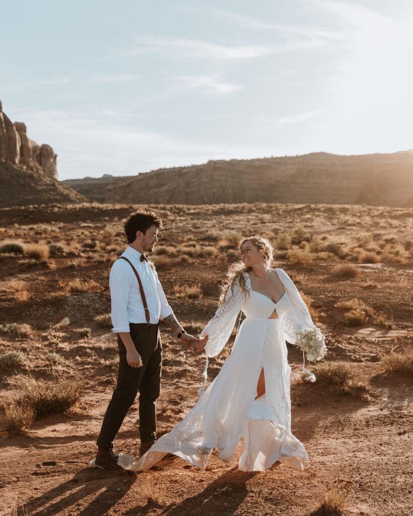 couple walks along rocky Moab desert during sunset