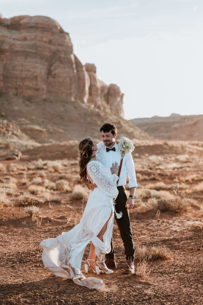 couple embraces in front of rock structure of Moab desert