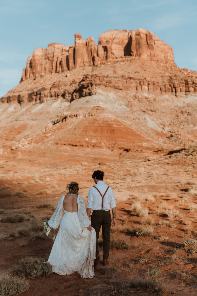 couple walks along rocky Moab desert during sunset