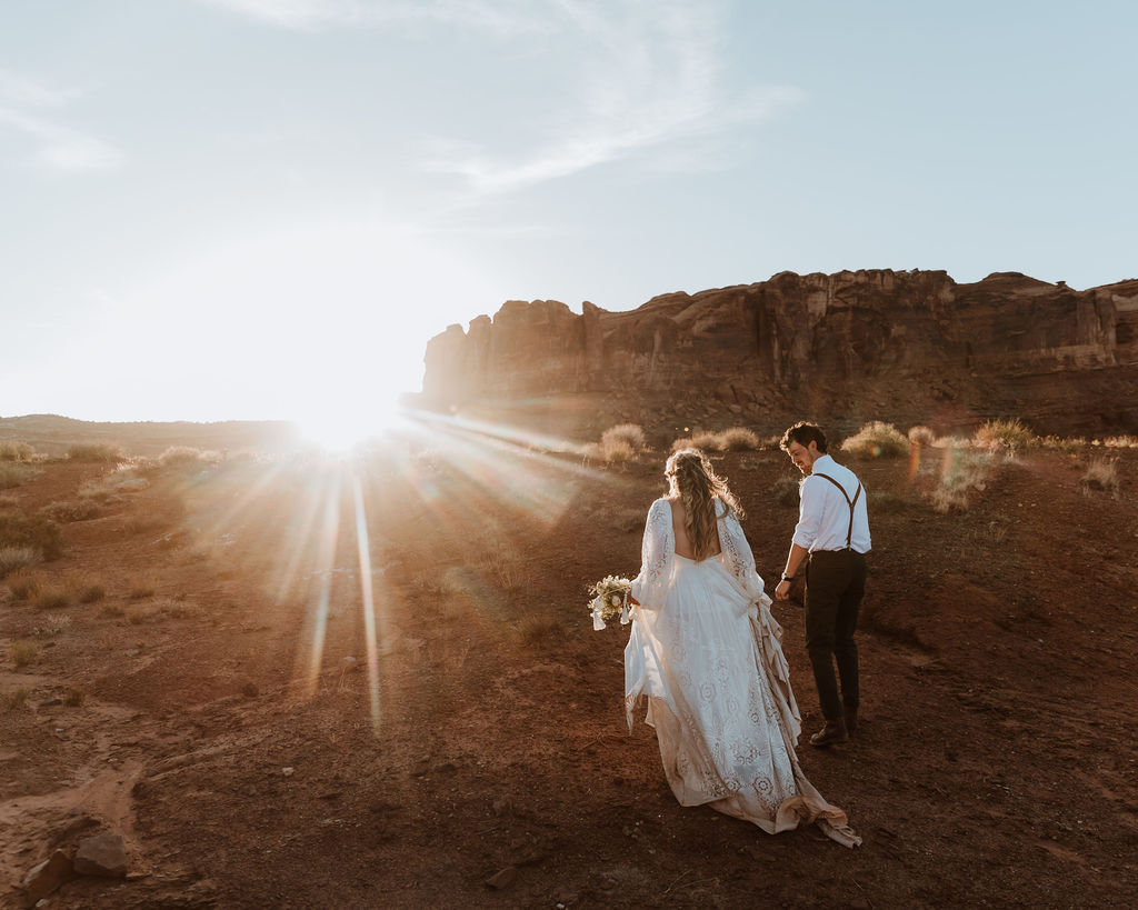couple walks along rocky Moab desert during sunset