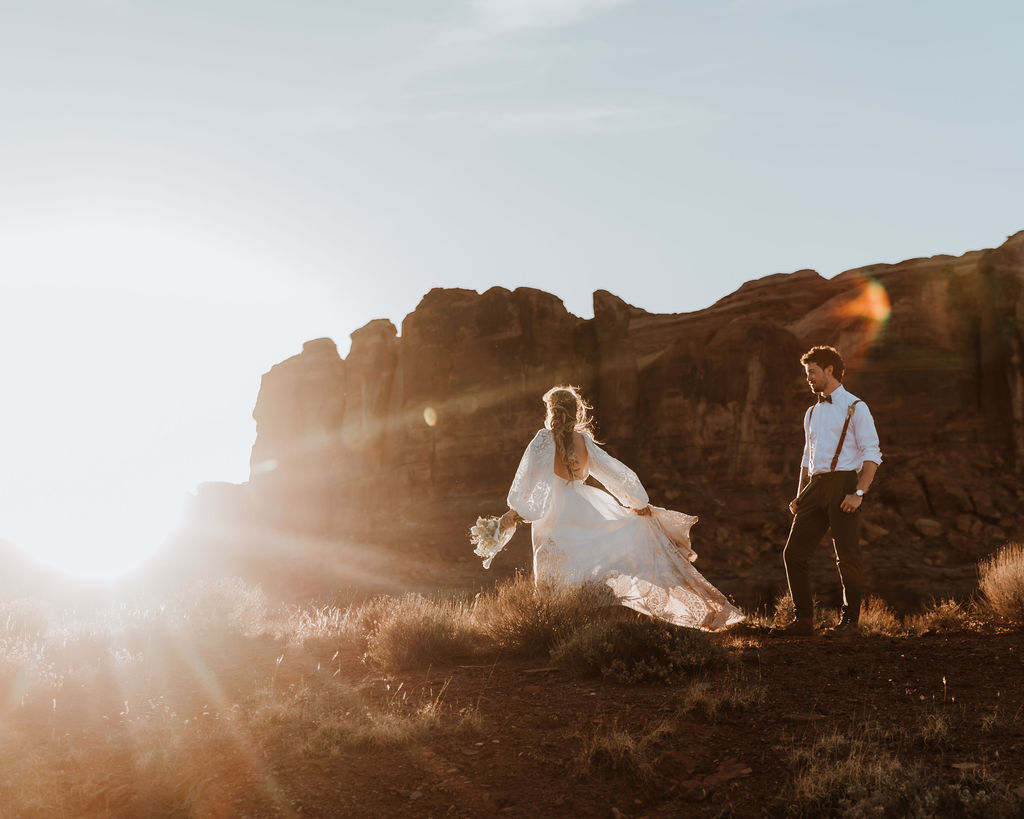 couple walks along rocky Moab desert during sunset