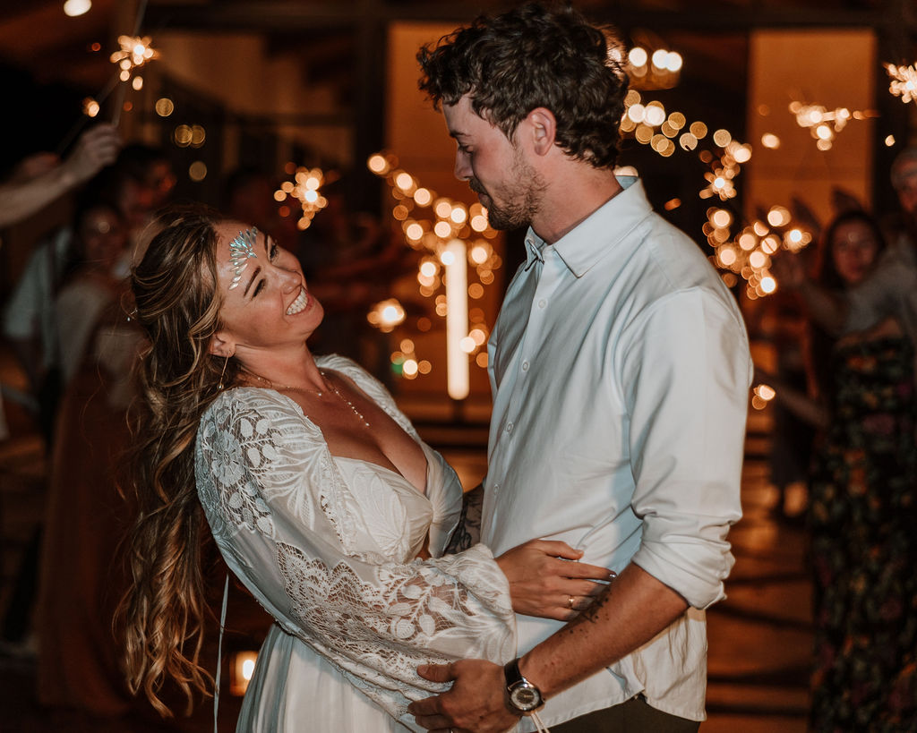 couple smile at each other at the end of sparkler send off