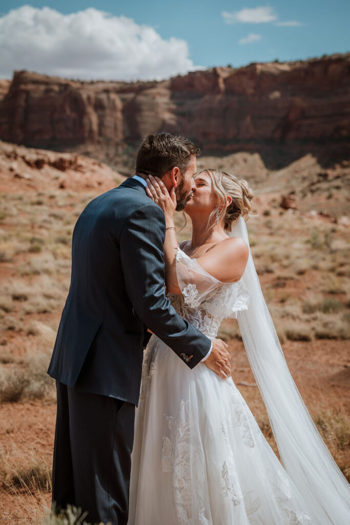couple kiss surrounded by Moab's rocky red landscape 