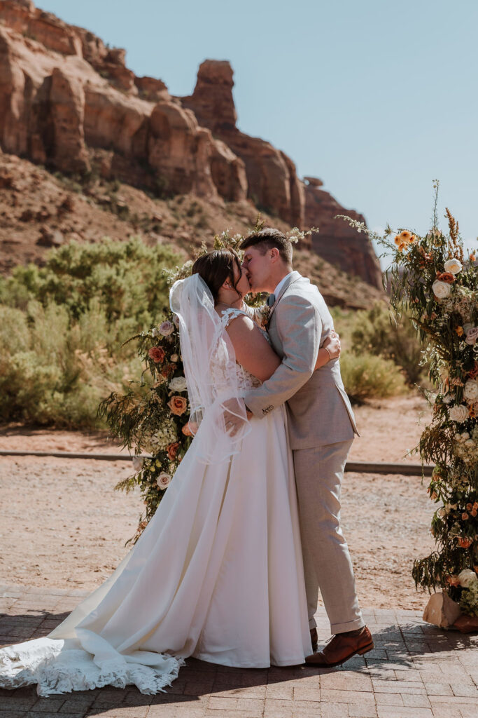 couple kiss during ceremony with Moab rocky landscape in the background