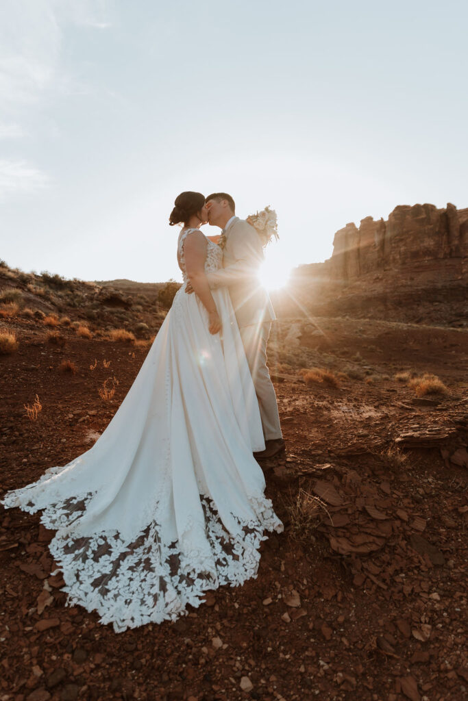 couple kiss during sunset in Moab's rocky red landscape