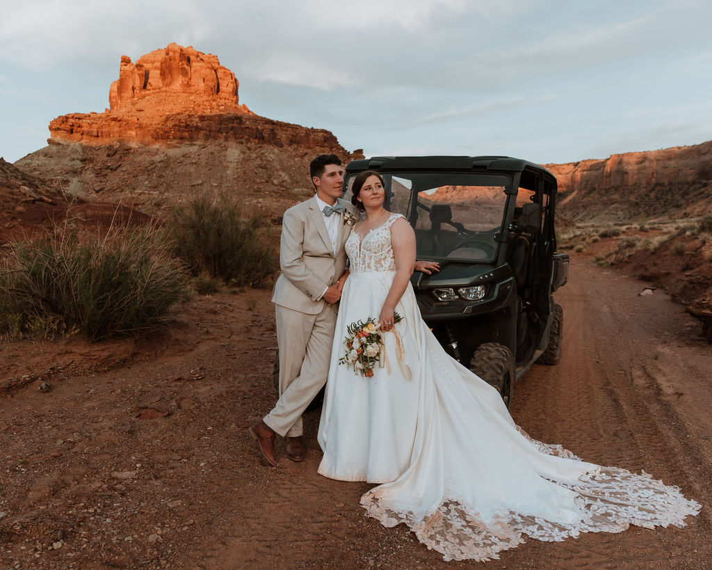 couple stands in front of jeep looking off into the distance