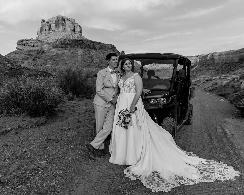 couple stands in front of jeep looking off into the distance