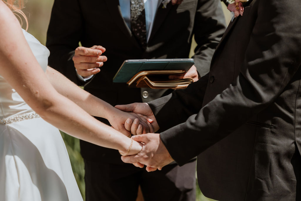 couple holds hands during wedding ceremony