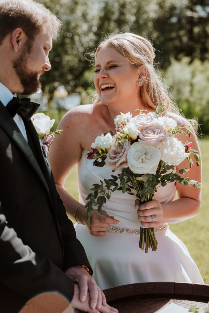 couple laugh together signing marriage certificate
