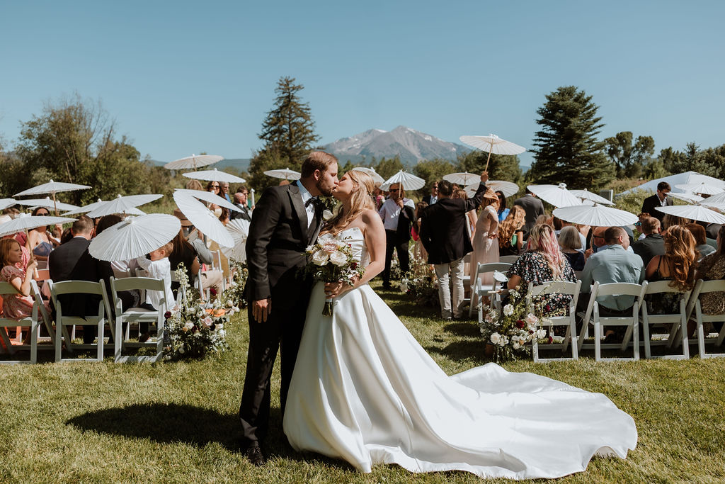 couple kiss after ceremony with guests in the background