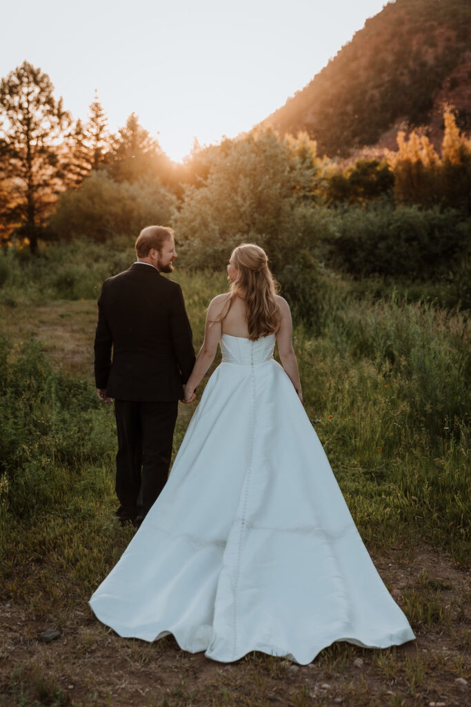 couple walk along grassy path at sunset at Spring Creeks Ranch