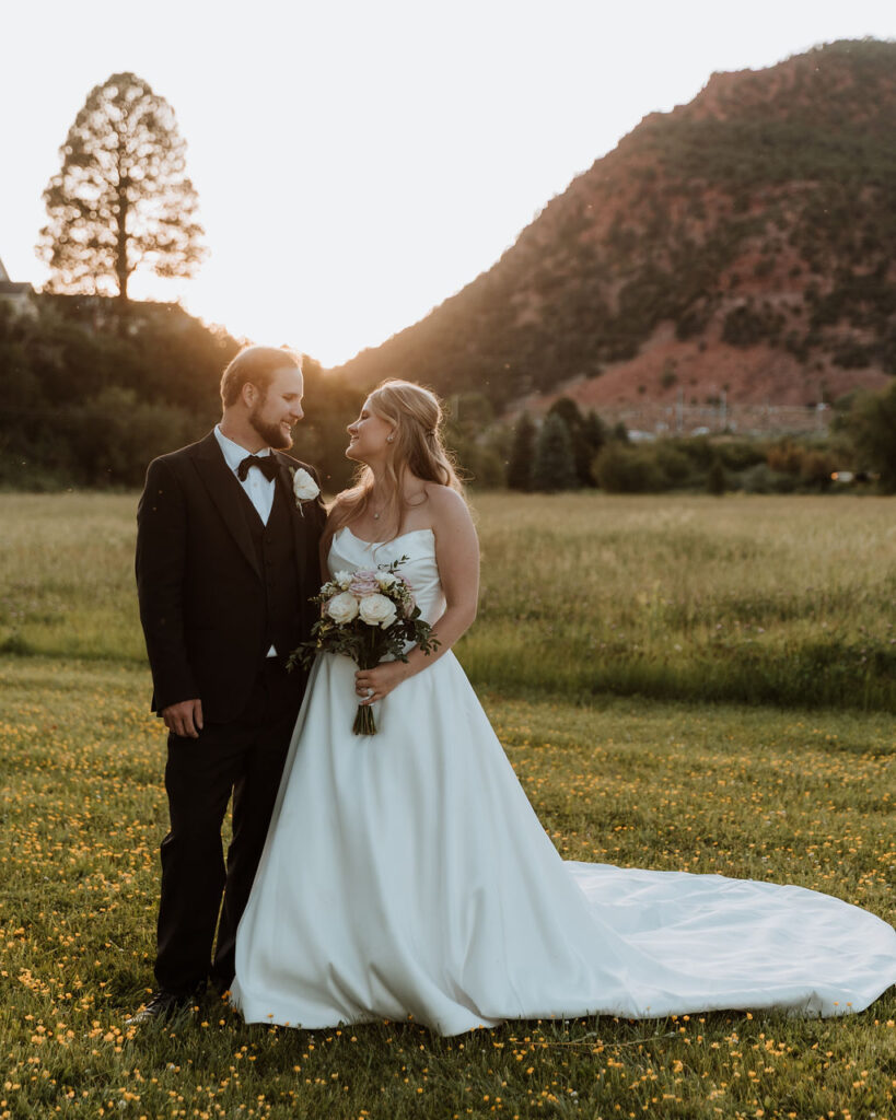 couple pose in grassy meadows at sunset at Spring Creeks Ranch